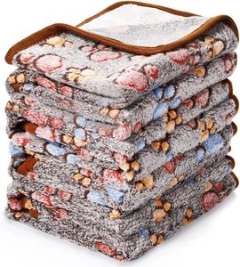 Close-up of stacked thick grey flannel pet blankets with colorful paw prints and soft texture