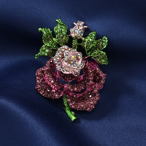 Elegant rose brooch with pink and green rhinestones on dark blue silk background
