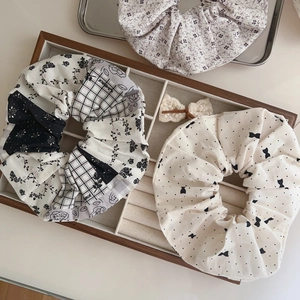Three-piece set of floral and checkered cotton scrunchies on a wooden tray