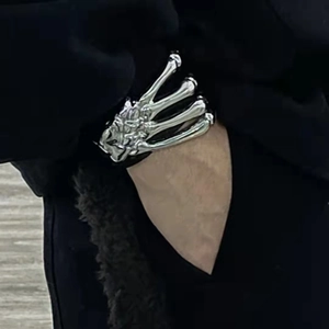 Detail of silver skeleton hand bracelet worn as a gothic style cuff over a black sleeve