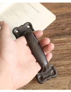 Close-up of vintage cast iron door handle held in hand showing rustic texture and bronze finish