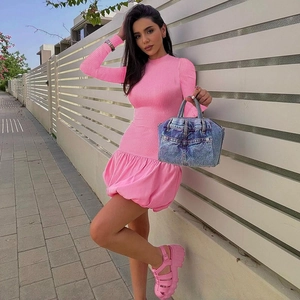 Détail de la robe moulante en tricot rose avec ourlet à volants et sac à main en denim