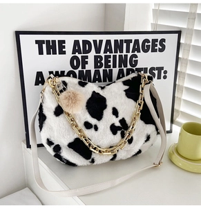 Detail of plush cow print tote bag featuring a chunky gold chain and soft faux fur texture