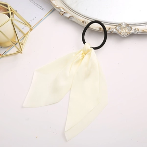 Close-up of a floral silk bow scrunchie with cream ribbons and vintage lifestyle props