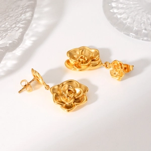 Close-up of 18K gold stainless steel rose earrings with layered 3D floral texture