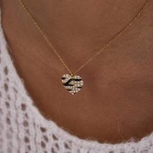 Close-up of heart necklace with gold finish, zebra pattern enamel and crystal stones