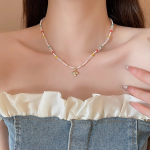 Detail of colorful beaded necklace with golden mushroom pendant on model neck