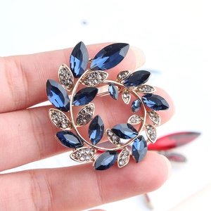 Detailed view of floral wreath brooch featuring blue marquise crystals and grey rhinestones