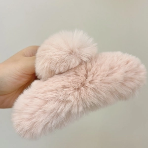 Detail of a large plush faux fur hair claw clip in soft light pink for autumn and winter