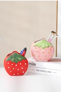 Detail of red and pink strawberry ceramic holders for pens and makeup brushes