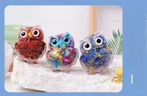 Detailed close-up of three crystal owl statues filled with colorful mineral stones and foil