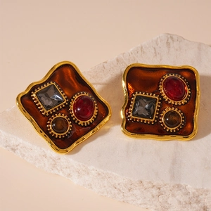 Macro shot of vintage gold earrings with resin stones on white marble base