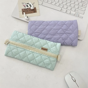Detailed macro view of quilted pastel zipper pencil cases in lavender and mint green colors