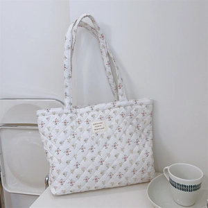 Détail du sac cabas fleuri matelassé montrant les coutures et l'étiquette en tissu