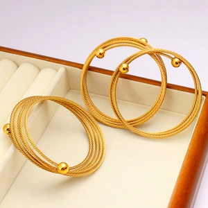 Dettaglio macro di bracciali a più fili intrecciati color oro in una scatola