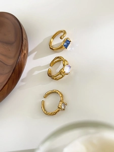 Detailed shot of three irregular gold rings with blue, opal, and zircon stone inlays