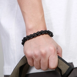 Detail of men's black stainless steel skull bead bracelet worn on wrist with contrast