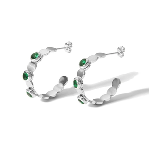 Detail showing silver C-shaped stainless steel earrings with inlaid green gemstones