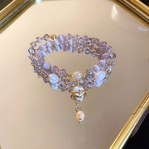 Détail d'un bracelet multicouche avec opale violette, perles et pendentif planète