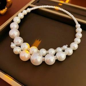 Detailed view of layered faux pearl choker with silver spacers on jewelry tray