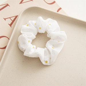 Macro shot of white chiffon scrunchie with yellow daisies on a magazine tray