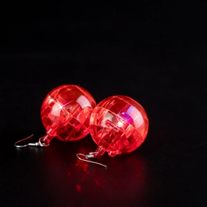 Macro shot of red glowing disco ball earrings with shining LED light on black background