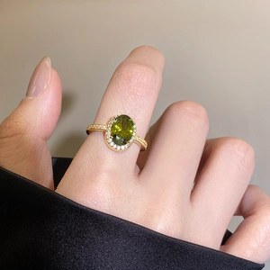 Close-up of 18k gold plated ring featuring an oval olive green zircon and pavé diamonds