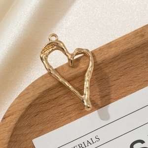 Macro view of a gold heart charm with irregular lava texture on a wooden tray