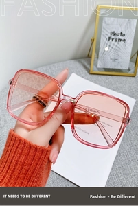 Close-up of pink square oversized sunglasses with gradient lenses being held by a hand