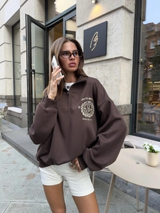 Vintage dark brown half-zip sweatshirt with chest badge print worn by a model outdoors