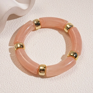 Detail of pink marble resin bracelet with polished gold metal spacers on warm background