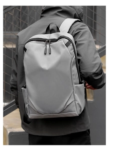 Minimalist grey water-resistant business laptop backpack shown on a commuter's back