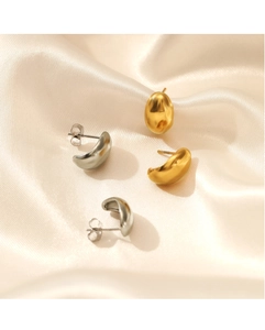 Detailed view of 18K gold and silver C-shaped stud earrings on champagne satin fabric