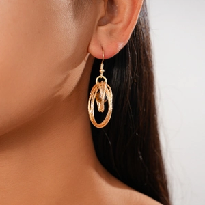 Close-up of bohemian multilayer gold hoop earrings with brown tiger eye beads on a model