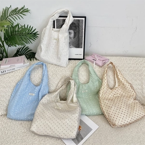 Detail shot of lightweight sequin tote bags in five pastel colors on soft texture