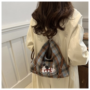 Detail of plaid wool backpack with cartoon dog embroidery on a beige trench coat