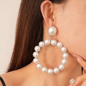 Gros plan d'un modèle portant de grandes boucles d'oreilles créoles en perles blanches