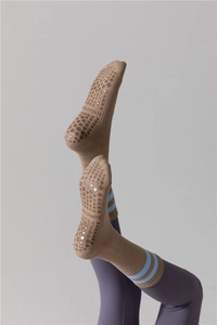 Détail de chaussettes de yoga marron avec rayures bleues et poignées en silicone antidérapantes