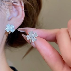 Detailed close-up of clover-shaped stud earrings featuring sparkling pavé crystals
