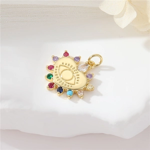 Detail of a gold heart-shaped evil eye pendant with colorful zircons on white stone