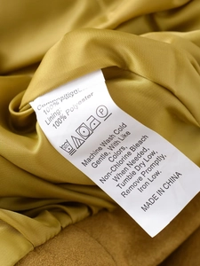 Macro detail of washing care label on a slim fit suede bomber jacket in ginger yellow