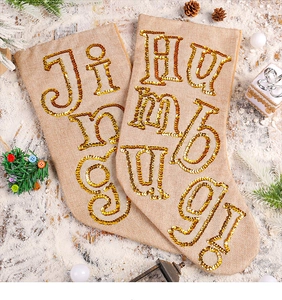 Detail of linen Christmas stockings with gold sequins featuring Jingle and Humbaloo text