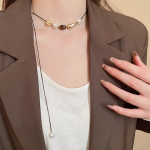 Detail of tiger eye stone and pearl flower pendant necklace on professional model