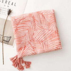 Detail of coral pink scarf featuring white geometric patterns and matching corner tassels