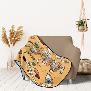 Detail of mushroom patterned yellow flannel blanket draped over a beige sofa in home setting