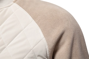 Detail of diamond-quilted cream fabric stitched with khaki fleece on a warm jacket