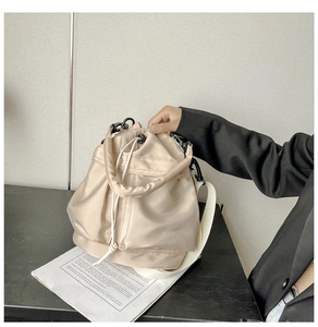 Detailed view of beige nylon drawstring bucket bag with smooth satin finish and wide strap