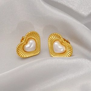 Vintage heart earrings in gold plated stainless steel with pearl center on silk background