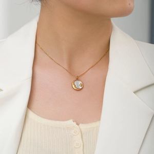 Close-up of a gold star and moon necklace with white shell pendant on a female model