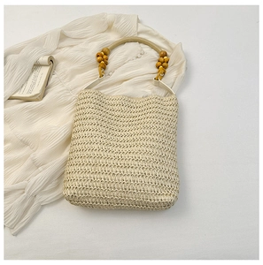 Close-up of beige woven straw bucket bag featuring a natural wooden bead handle